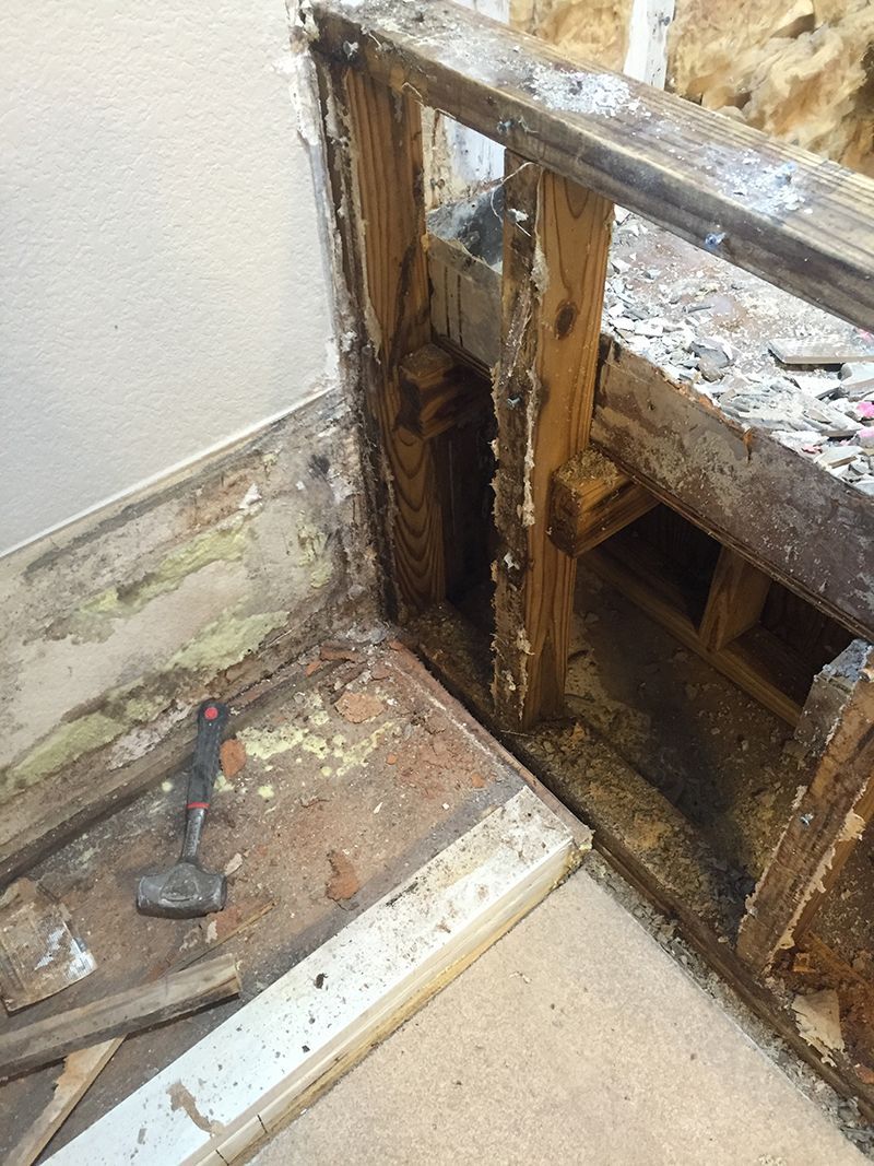 A hammer is sitting on the floor next to a hole in the wall.