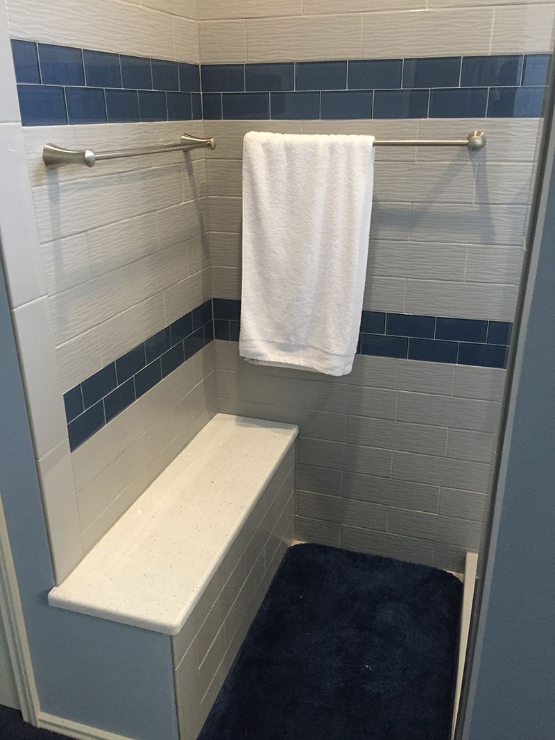 A shower with a bench and a towel hanging on the wall.