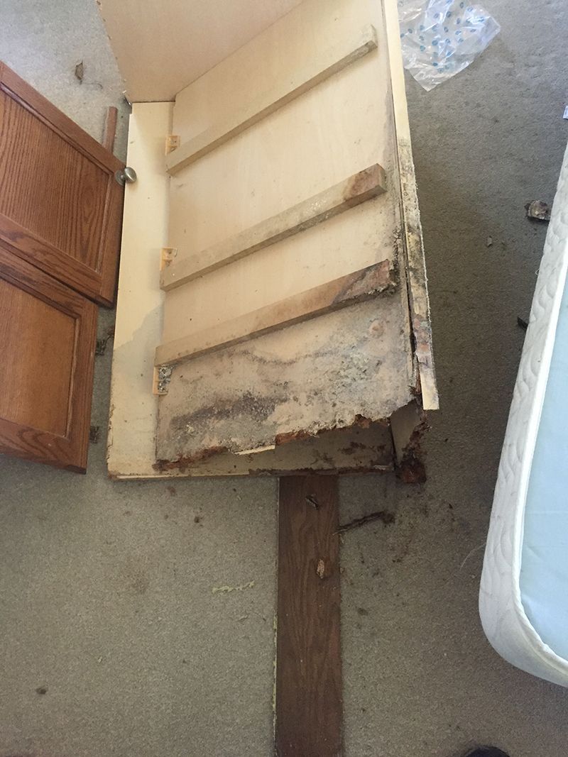 A piece of wood is sitting on the floor next to a mattress.