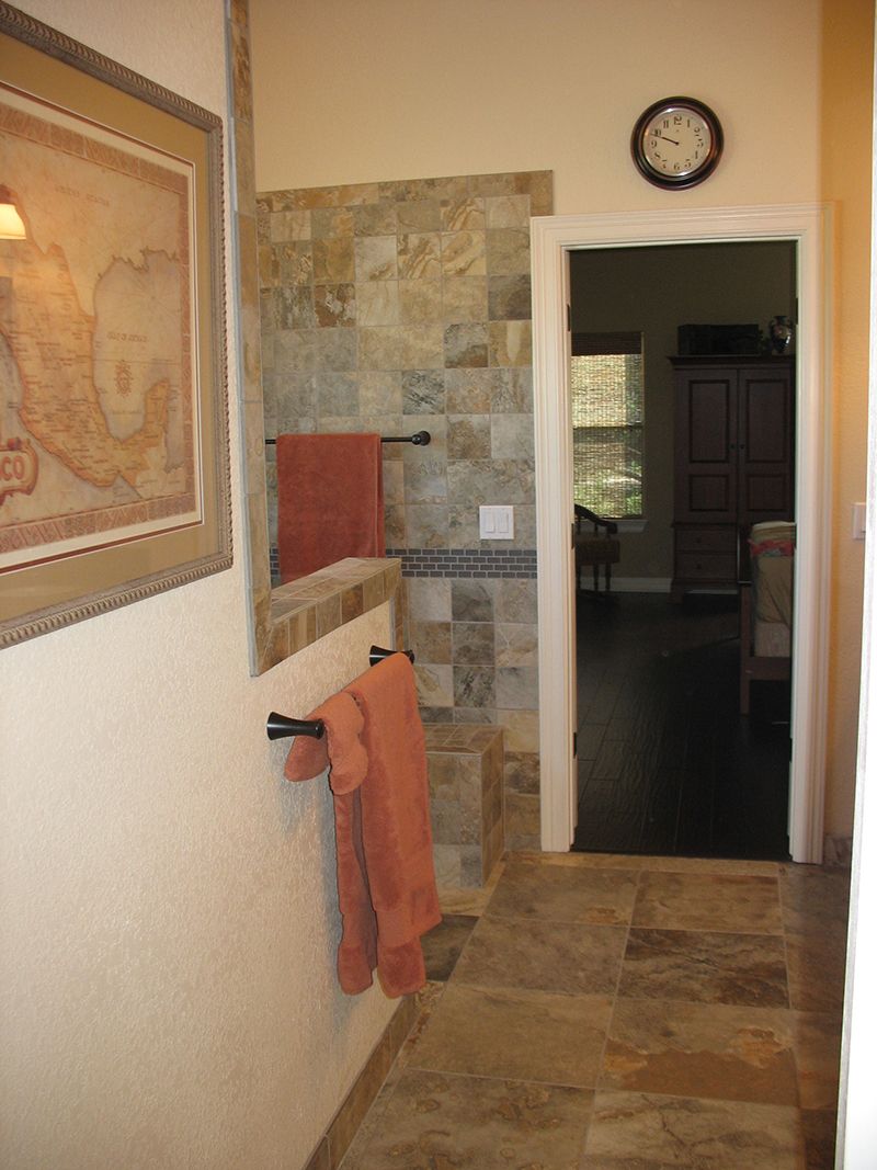 A hallway leading to a bathroom with a clock on the wall