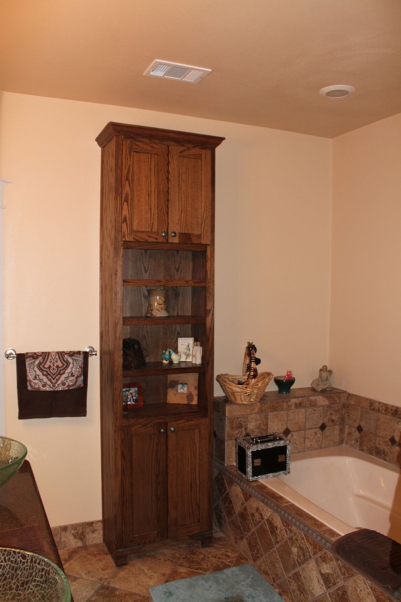 A bathroom with a bathtub and a wooden cabinet.