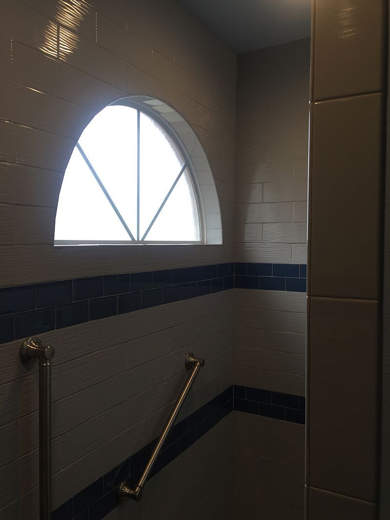 A bathroom with a window and a hand rail