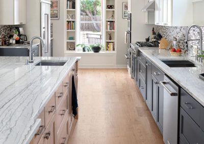 A kitchen with marble counter tops , stainless steel appliances , and wooden floors.