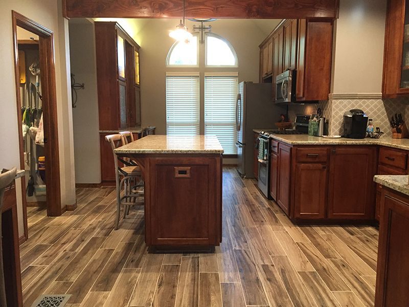 A kitchen with wooden cabinets and a large island in the middle.