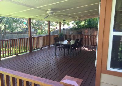 A large deck with a table and chairs and a ceiling fan.
