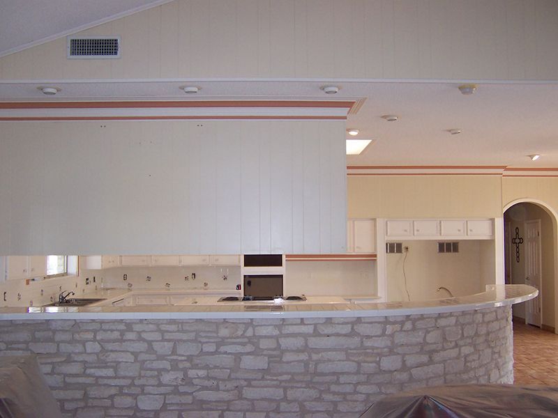 A kitchen with a stone counter top and white cabinets