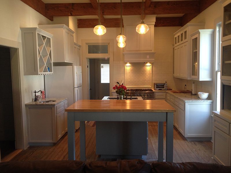 A kitchen with white cabinets and a large island in the middle