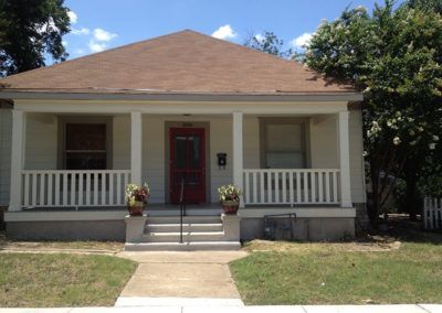 A white house with a red door and white porch