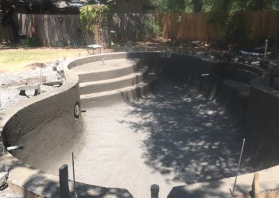 A large swimming pool is being built in a backyard.