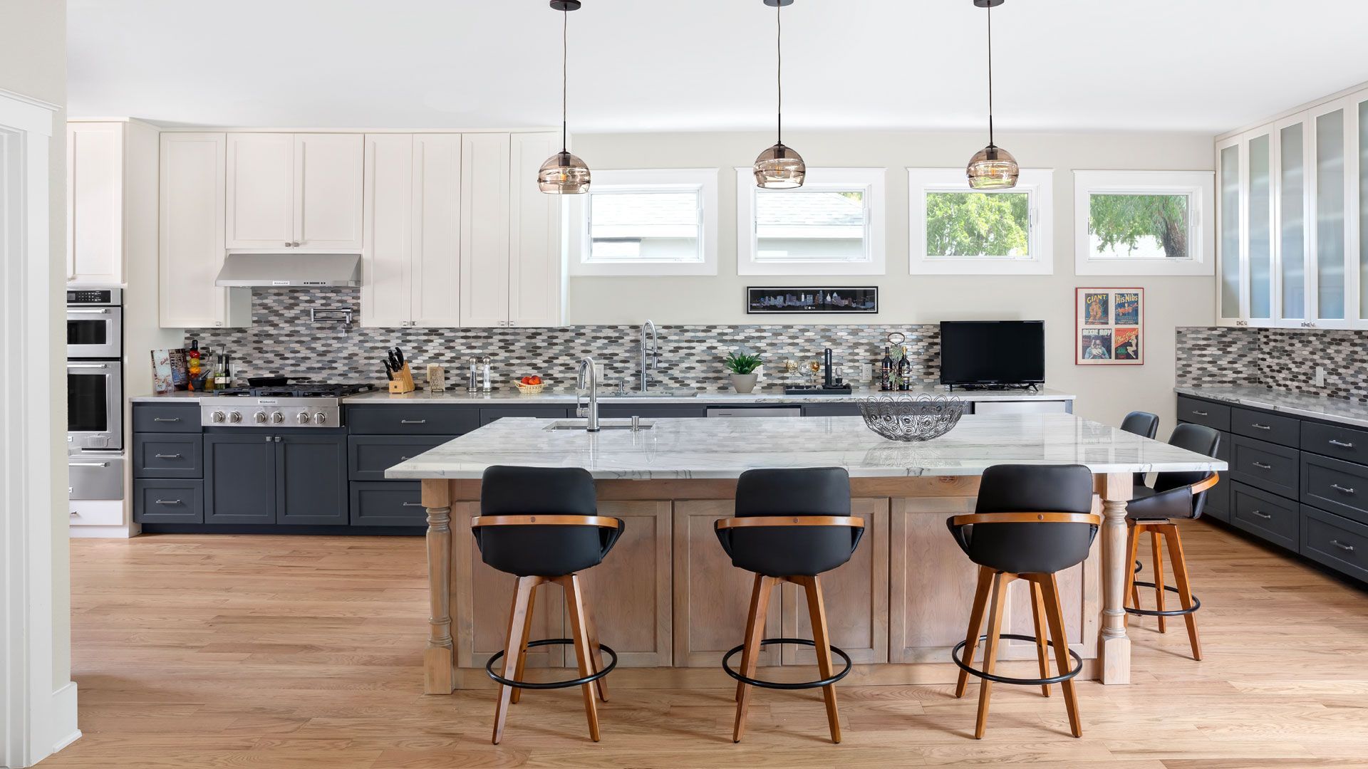 A kitchen with a large island and stools in it.