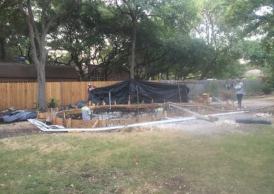 A group of people are working on a swimming pool in a backyard.