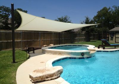 A large swimming pool with a shade sail over it