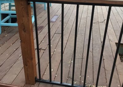 A close up of a metal railing on a wooden deck.
