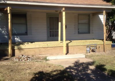 A white house with a porch that is being built.