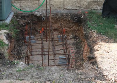 A concrete foundation is being built in a hole in the ground.