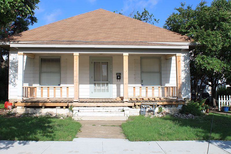 A white house with a brown roof and a porch