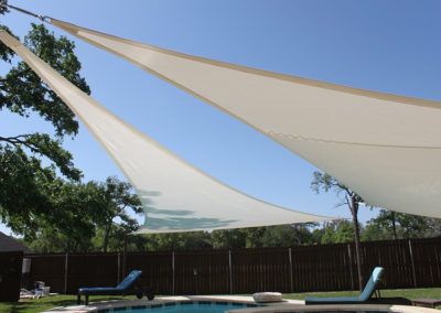 A swimming pool with a shade sail over it