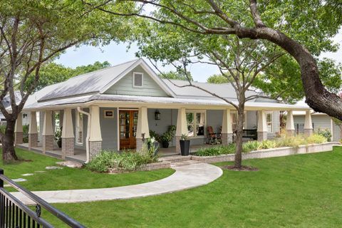 A house with a porch and a tree in front of it.