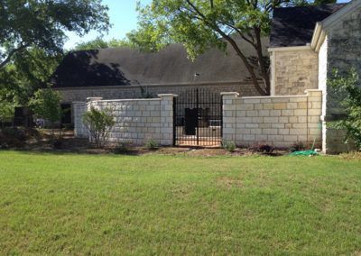 A brick wall with a gate in front of a house.