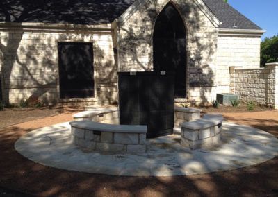 A white building with a black door and a stone patio in front of it.