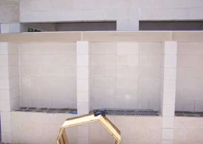 A white tiled wall with a wooden sculpture in front of it
