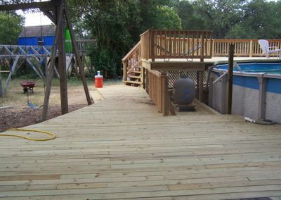 A wooden deck with a pool in the background