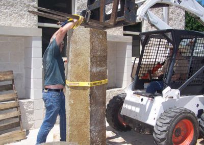 A man is lifting a large piece of stone with a forklift.