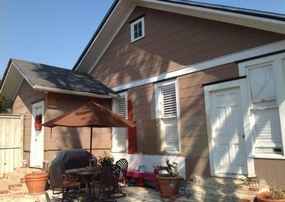 A house with a table and chairs under an umbrella