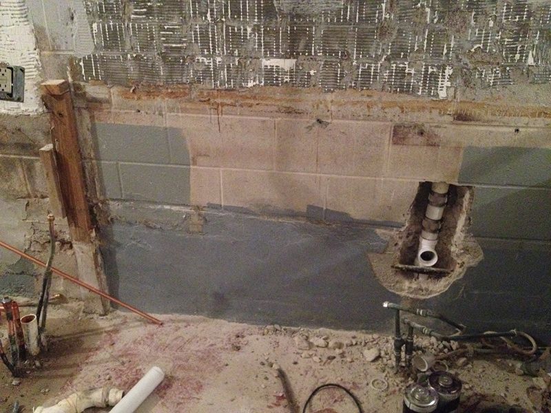 A bathtub is being remodeled with a hole in the wall.