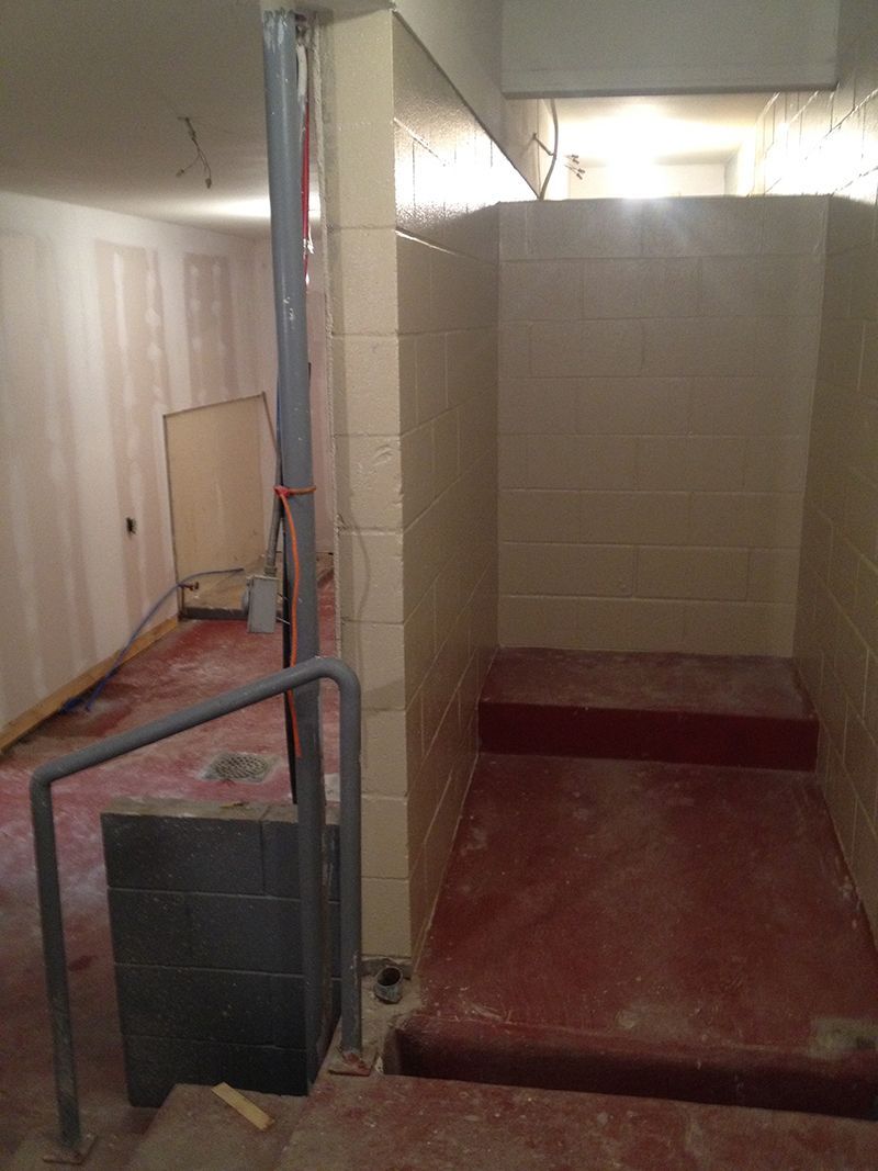 An empty room with a staircase leading up to a bathroom.