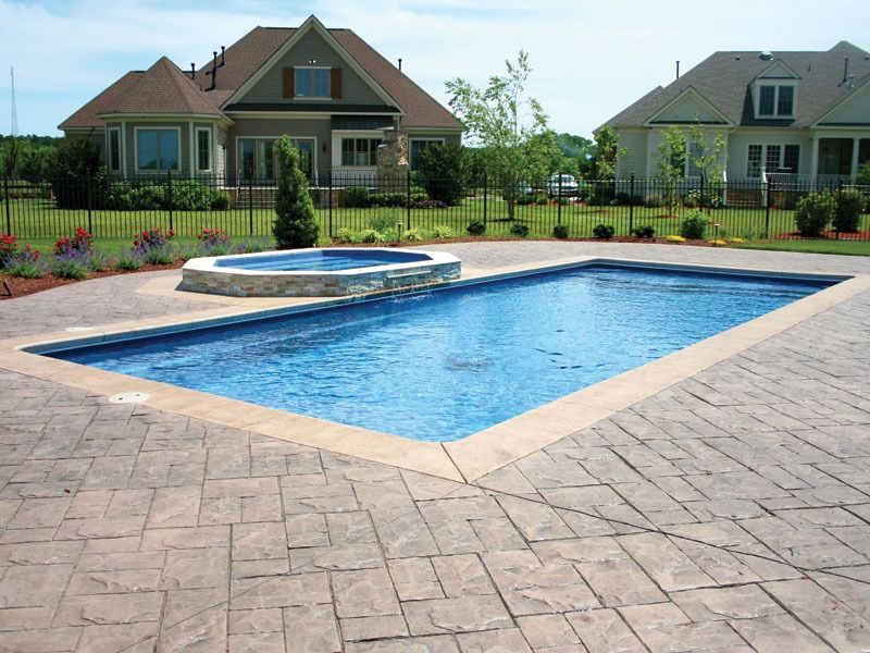 Backyard swimming pool with stone patio and two houses in the background