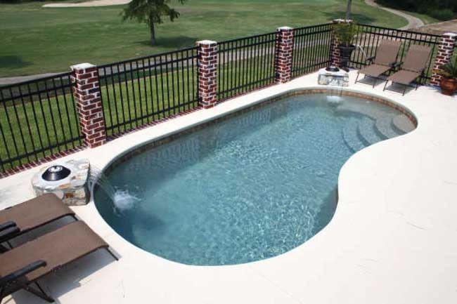 Backyard swimming pool with lounge chairs, brick railing, and grassy yard beyond
