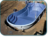 Blue molded playground slide under construction on a dirt lot