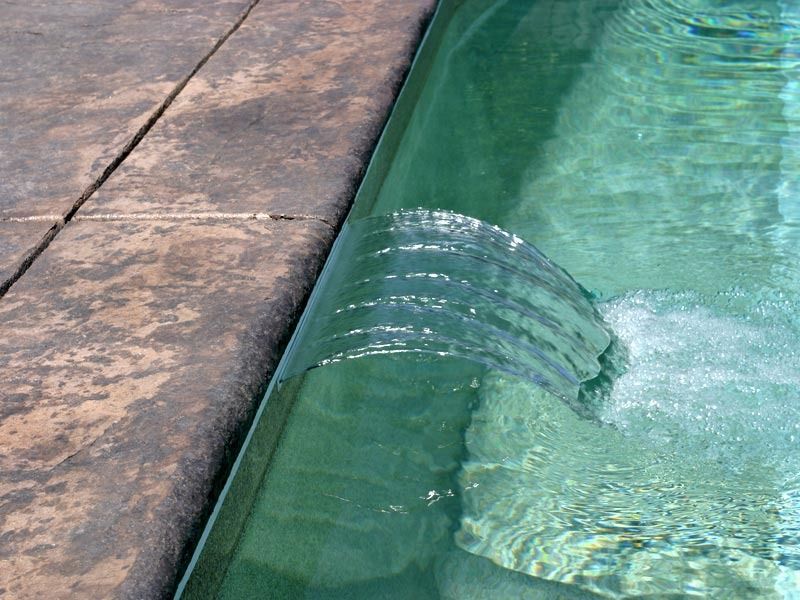 Broken pool edge spilling water into turquoise pool