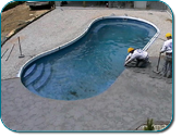 Outdoor swimming pool with two people cleaning the water using a vacuum and net
