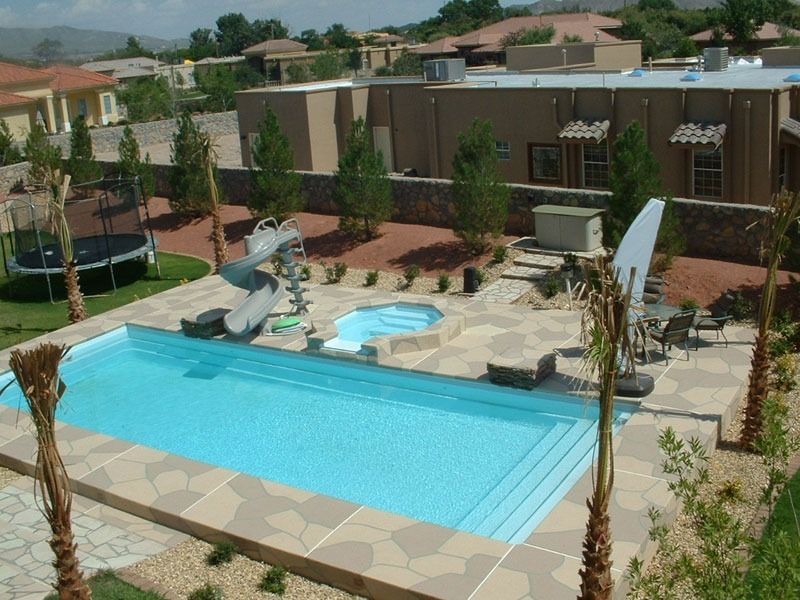 Apartment pool with a blue diving board, lounge chairs, and landscaped courtyard under a clear sky