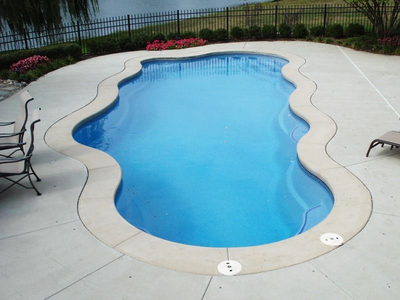 Backyard swimming pool with light blue water and a concrete deck, viewed from above