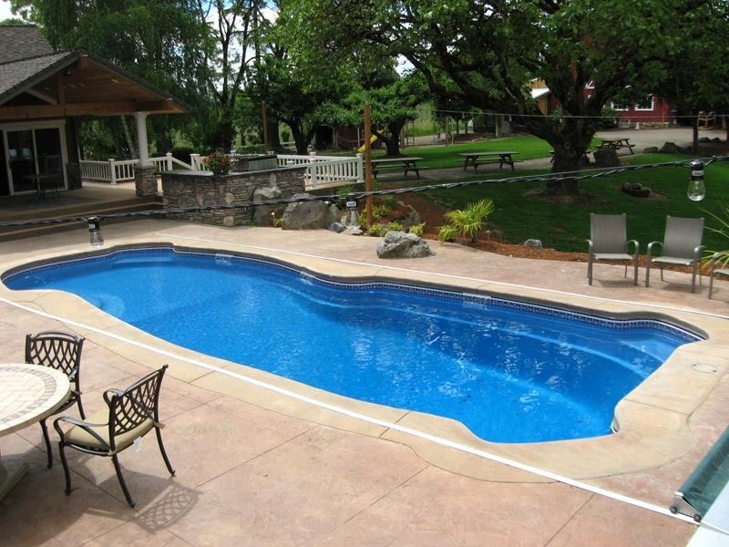 Backyard swimming pool with blue water, patio chairs, and a shaded gazebo in a garden setting