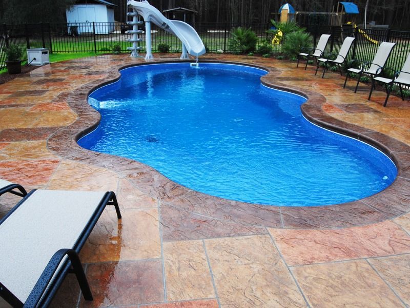 Backyard pool with blue water, tan stone deck, lounge chairs, and a decorative dolphin fountain