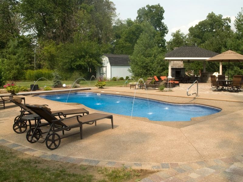 Backyard pool with lounge chairs, patio, and gazebo surrounded by trees