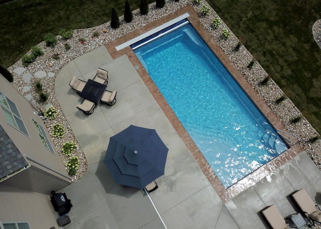 Overhead view of a backyard pool with patio furniture and a blue umbrella