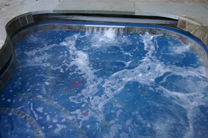 Blue hot tub water bubbling and splashing against the curved pool edge