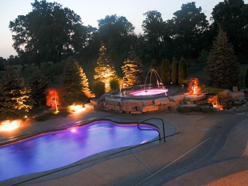 Backyard pool and spa at dusk, lit with purple and orange landscape lighting