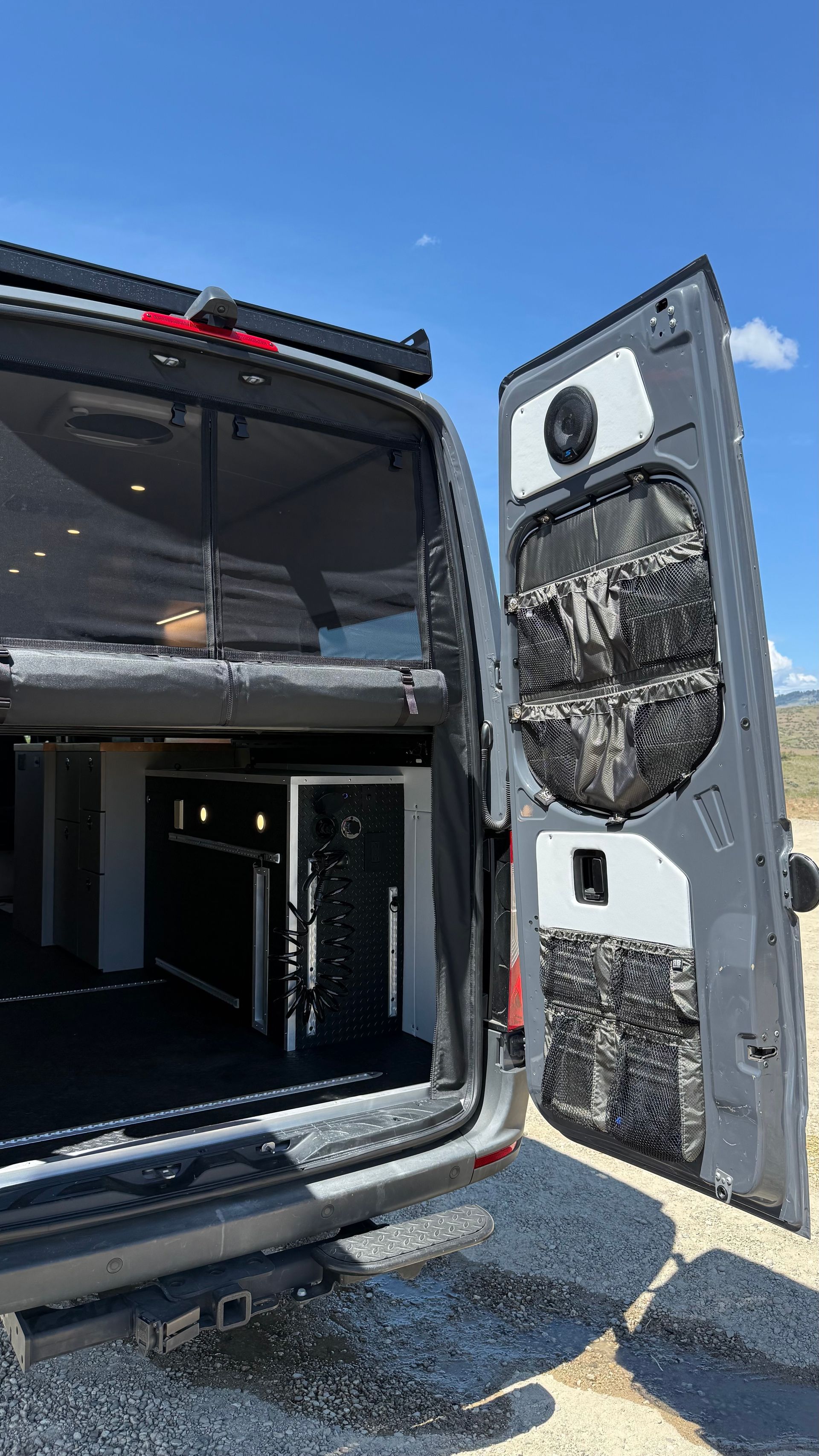 Open cargo van with rear door open, showing empty interior and mounted fans on the door.