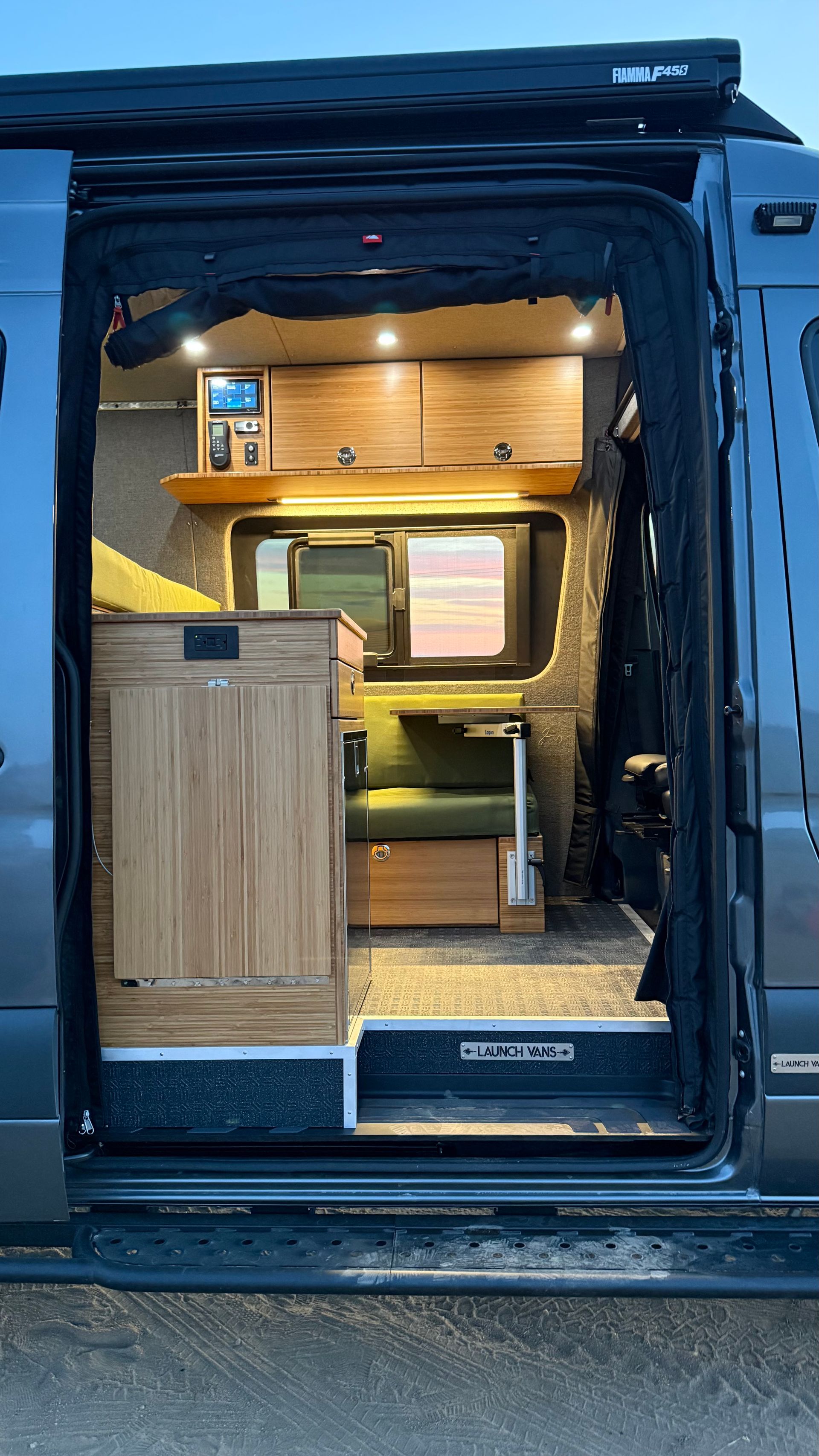 Open van with a cozy wood-paneled camper interior and a small kitchen visible through the side door