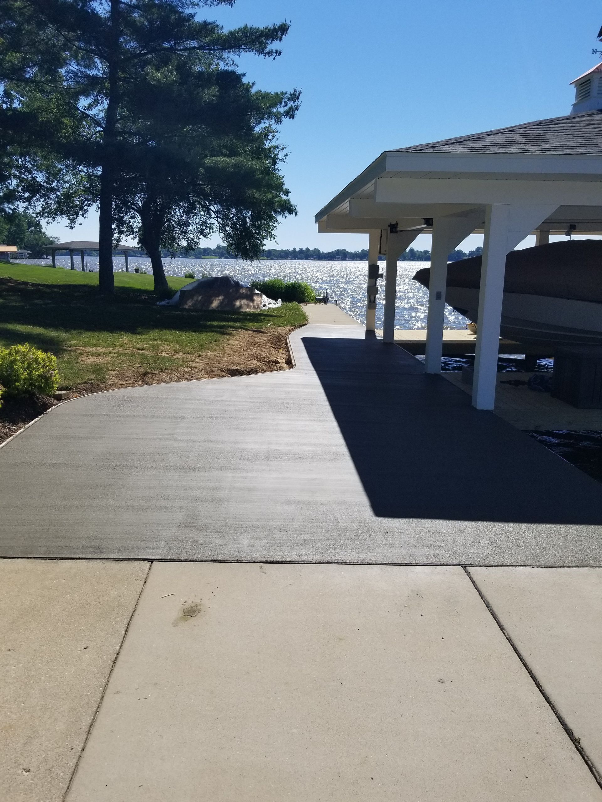 A boat is parked under a carport next to a lake