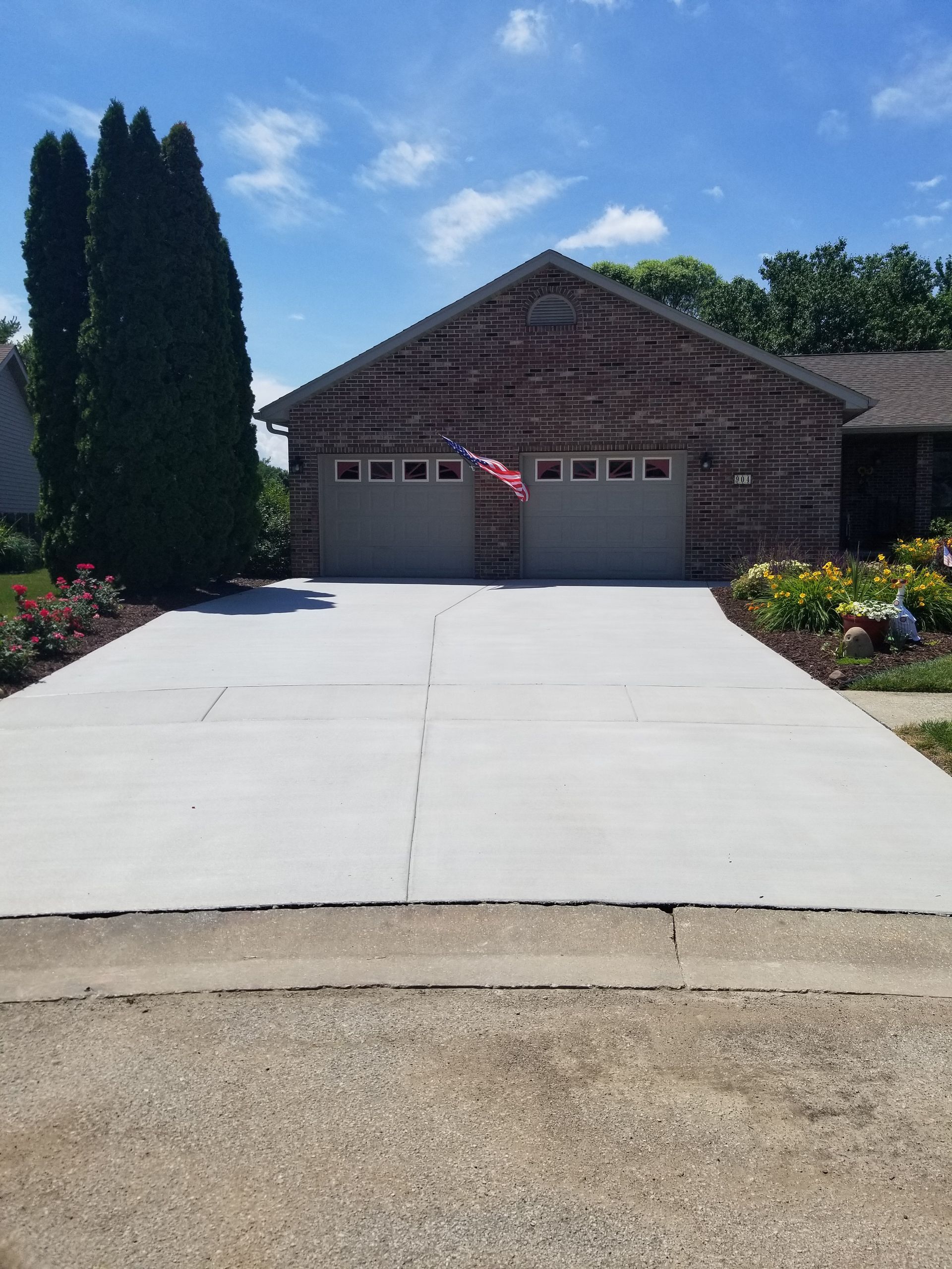 A brick house with a concrete driveway leading to it