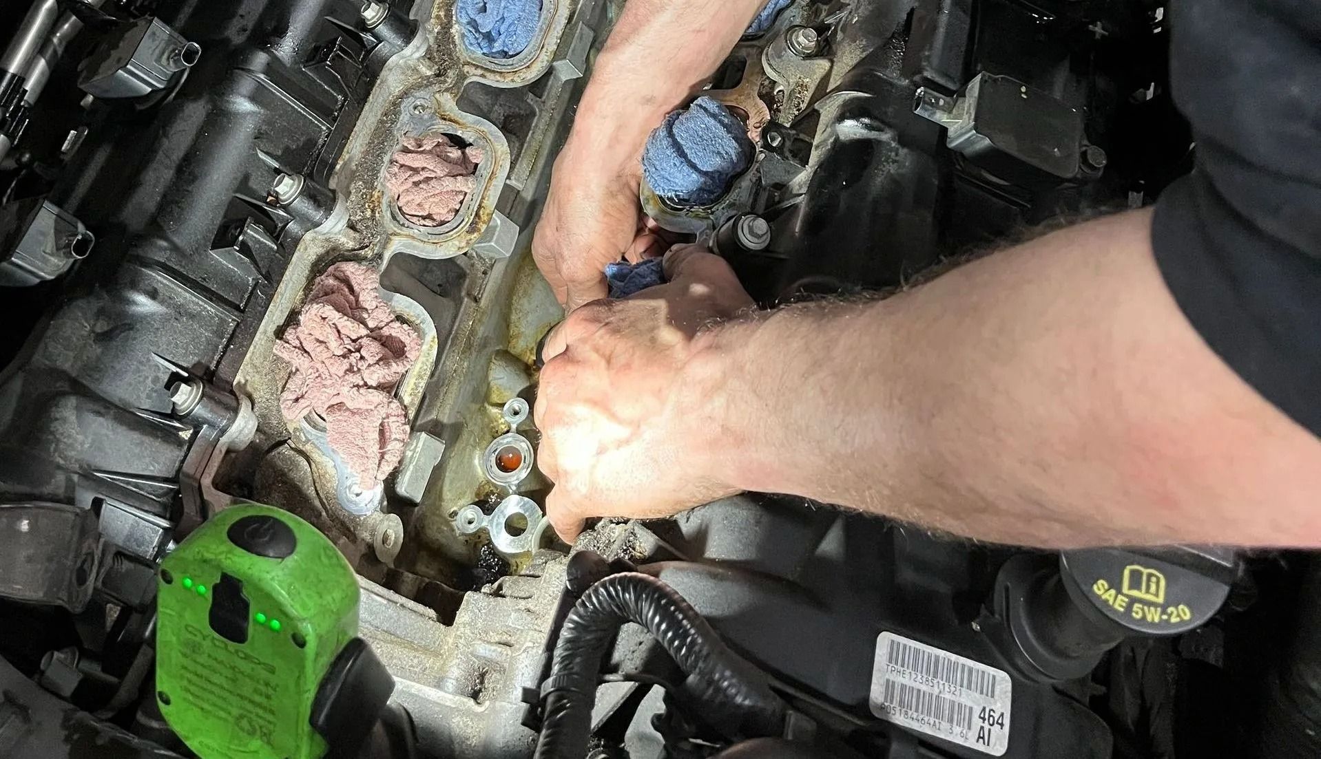 Hands working on an engine bay; removing or replacing components.