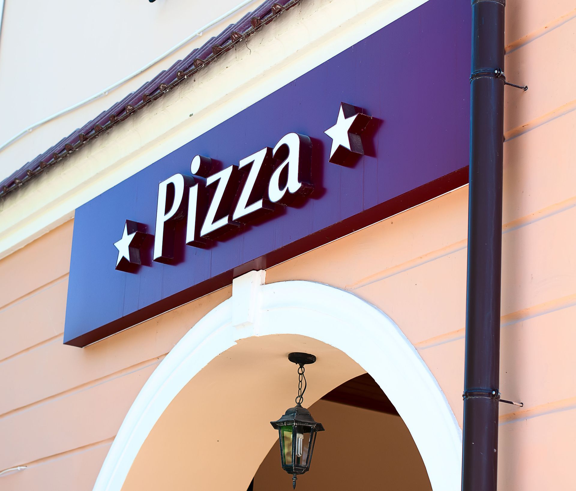 Pizza sign on a purple background, with white text and stars, over an archway.