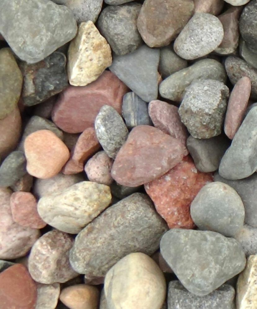 A close-up view of a pile of smooth, multi-colored river stones and pebbles in shades of gray, brown, and pink.